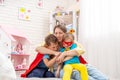 Happy young woman is playing with her children as superheroes. Hugs them Royalty Free Stock Photo