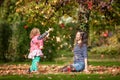 Mother and identical twins having fun with autumn leaves in the park, blond cute curly girls, happy kids, girls in pink jacket Royalty Free Stock Photo