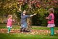 Mother and identical twins having fun with autumn leaves in the park, blond cute curly girls, happy kids, girls in pink jacket Royalty Free Stock Photo