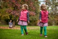 Mother and identical twins having fun in autumn in the park, blond cute curly girls, happy family, beautiful girls in pink jackets Royalty Free Stock Photo