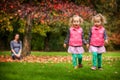 Mother and identical twins having fun in autumn in the park, blond cute curly girls, happy family, beautiful girls in pink jackets Royalty Free Stock Photo