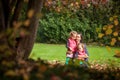 Mother and identical twins having fun in the park in autumn, blond cute curly girls, happy family, beautiful girls in pink jackets