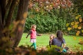 Mother and identical twins having fun in the park in autumn, blond cute curly girls, happy family, beautiful girls in pink jackets