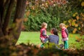 Mother and identical twins having fun in the park in autumn, blond cute curly girls, happy family