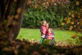 Mother and identical twins having fun in the park in autumn, blond cute curly girls, happy family
