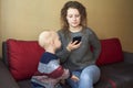 Mother is indifferent to her little son, mom looks at the smartphone, the child needs attention