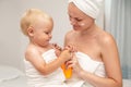 Mother and infant baby in white towels after bath apply sunscreen or after sun lotion or cream. Children skin care. Spf, skin