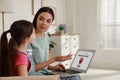 Mother installing parental control app on laptop to ensure her child`s safety at home