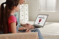 Mother installing parental control app on laptop to ensure her child`s safety at home
