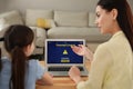 Mother installing parental control app on laptop to ensure child`s safety at home