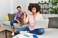 Mother of interracial family working using computer laptop at home pointing up looking sad and upset, indicating direction with Royalty Free Stock Photo