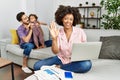 Mother of interracial family working using computer laptop at home waiving saying hello happy and smiling, friendly welcome Royalty Free Stock Photo