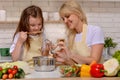 Mother and kid daughter preparing healthy food and having fun home on the background of the kitchen Royalty Free Stock Photo