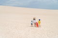 Mother with kids climbing up sand dune while carrying a sandboard Royalty Free Stock Photo