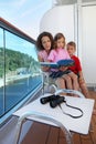 Mother, kids consider book on ship deck