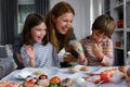 Mother with kids decorating cookies for Halloween