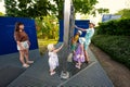 Mother with kids play with moving metal sticks frame at exhibition outdoor
