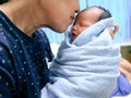 Mother kiss sweet newborn baby in her hands. Happy family concept. Royalty Free Stock Photo