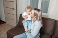 Mother kisses baby and hugs. concept of happy motherhood. mother and child sitting on sofa at home