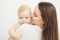 Mother kisses child in cheek, baby rests on mom shoulder Royalty Free Stock Photo