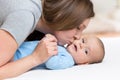 Mother kisses her baby while playing on white bed Royalty Free Stock Photo