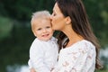 A mother kisses her two-year-old son. The son is happy and smiling. Mother`s day Royalty Free Stock Photo