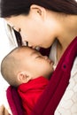 Mother kissing baby in baby carrier Royalty Free Stock Photo