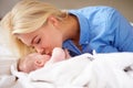 Mother Kissing Baby Girl As They Lie In Bed Together Royalty Free Stock Photo