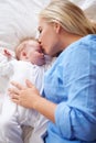 Mother Kissing Baby Girl As They Lie In Bed Together Royalty Free Stock Photo