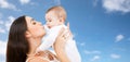 Mother kissing baby over sky background Royalty Free Stock Photo