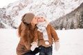 Mother kissing child outdoors among snow-capped mountains Royalty Free Stock Photo