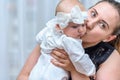 Mother kissing her baby girl. Cute toddler dressed in whites Royalty Free Stock Photo