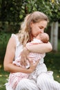 Mother is kissing her baby girl outdoors on summer day. Summer family time and fresh air concept Royalty Free Stock Photo