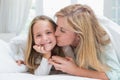 Mother kissing her daughter on the cheek in the bed Royalty Free Stock Photo