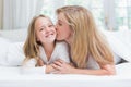 Mother kissing her daughter on the cheek in the bed Royalty Free Stock Photo