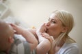 Mother kissing her little baby boy legs on bed at home. Royalty Free Stock Photo