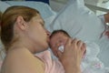 A mother kissing her newborn baby sleep in bed Royalty Free Stock Photo