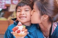 Mother kissing her son smiling while eating strawberry dessert ice cream in japanese cafe Royalty Free Stock Photo