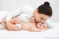 Mother kissing her sweet adorable baby in bed Royalty Free Stock Photo