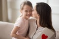 Mother kissing little daughter on cheek, thanking for gift postcard