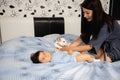 Pregnant Mother laying with her baby son on the bedroom bed playing and having fun - Asian mixed ethnicity child Boy Royalty Free Stock Photo