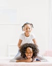 Mother lays on bed with playful daughter