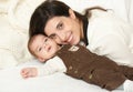 Mother lie with baby on bed, happy family portrait on white background, yellow toned Royalty Free Stock Photo