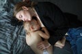 Mother lies on the bed and breastfeeds her infant daughter