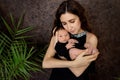 Mother lies on the bed with a newborn baby on a dark background, hugs her son 7 days, family day, mother`s love and care