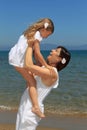 Mother lifting daughter up on beach