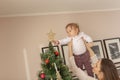 Mother lifting her son to place tree topper on Christmas tree Royalty Free Stock Photo