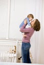 Mother lifting son from crib in bedroom Royalty Free Stock Photo