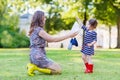 Mother and little adorable child in yellow and red rubber boots Royalty Free Stock Photo