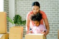 Mother and little American African girl help together to set or pack paper box or carton during move to new house, they look happy Royalty Free Stock Photo